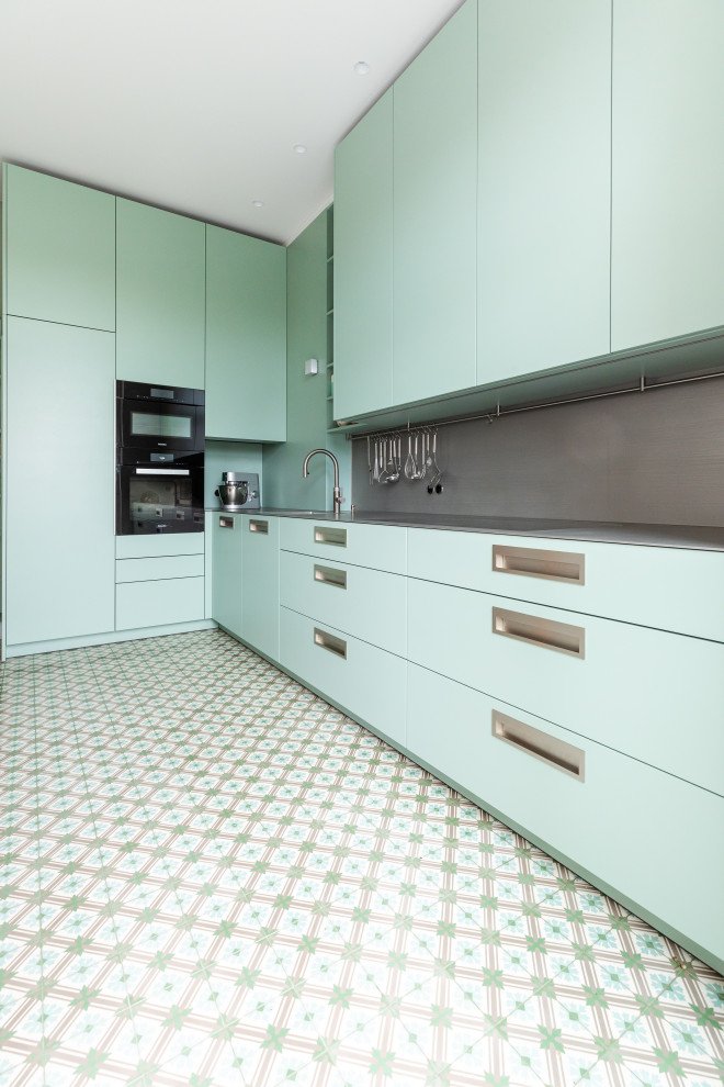 Exempel på ett mellanstort modernt grå grått kök, med en integrerad diskho, släta luckor, gröna skåp, bänkskiva i rostfritt stål, grått stänkskydd, stänkskydd i metallkakel, svarta vitvaror och flerfärgat golv