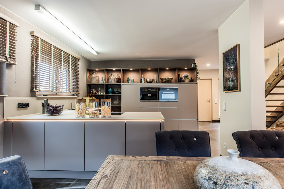 Immagine di una cucina design di medie dimensioni con penisola, top beige, pavimento marrone, lavello da incasso, ante lisce, ante marroni e elettrodomestici neri