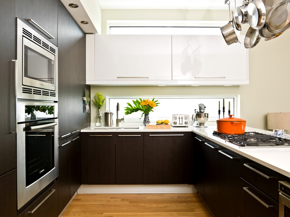 Esempio di una cucina minimal con lavello sottopiano, ante lisce, ante in legno bruno, elettrodomestici in acciaio inossidabile, pavimento in legno massello medio e penisola