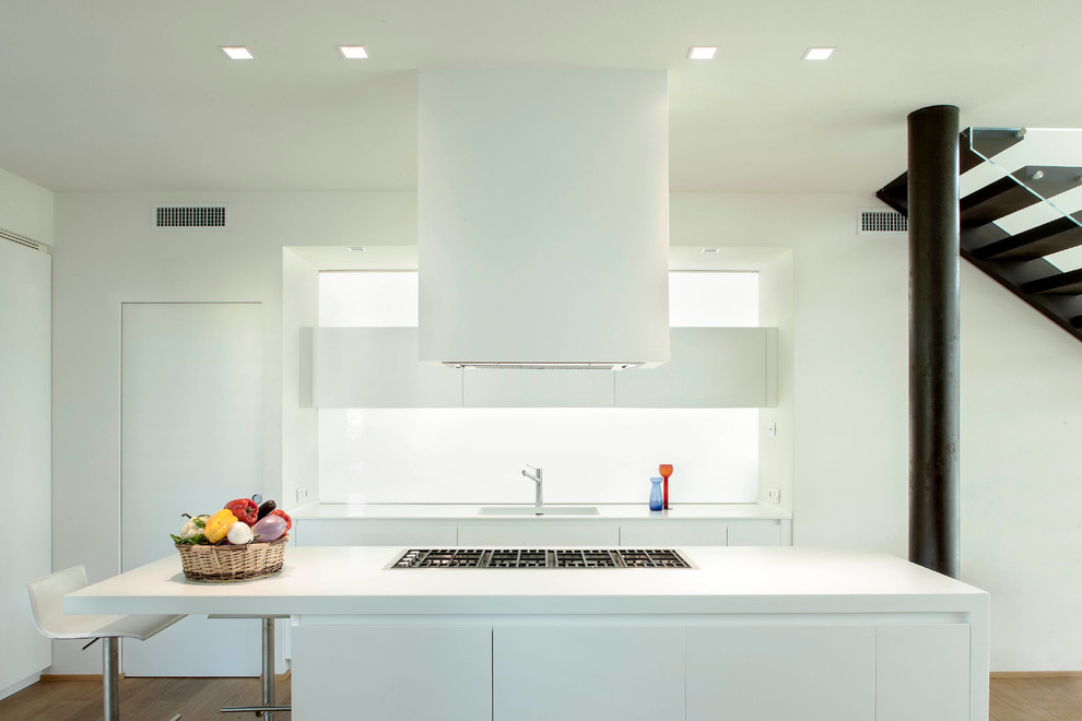 Medium sized contemporary single-wall kitchen/diner in Berlin with an integrated sink, flat-panel cabinets, white cabinets, wood worktops, white splashback, glass sheet splashback, white appliances, medium hardwood flooring and an island.