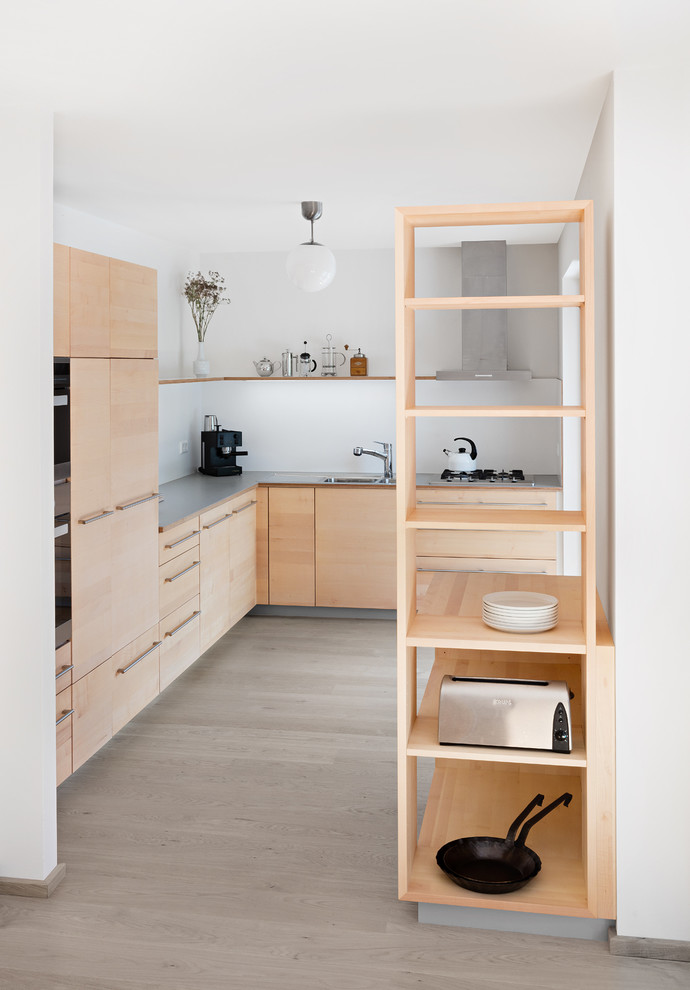 Design ideas for a medium sized contemporary l-shaped open plan kitchen in Stuttgart with flat-panel cabinets, light wood cabinets, laminate countertops, grey worktops, white splashback, integrated appliances, light hardwood flooring, beige floors, a built-in sink and no island.