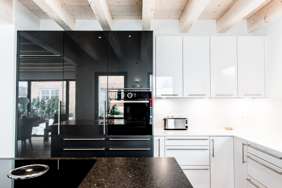 Mittelgroße Moderne Küche in L-Form mit flächenbündigen Schrankfronten, weißen Schränken, Küchenrückwand in Weiß, schwarzen Elektrogeräten, Kücheninsel und weißer Arbeitsplatte in München
