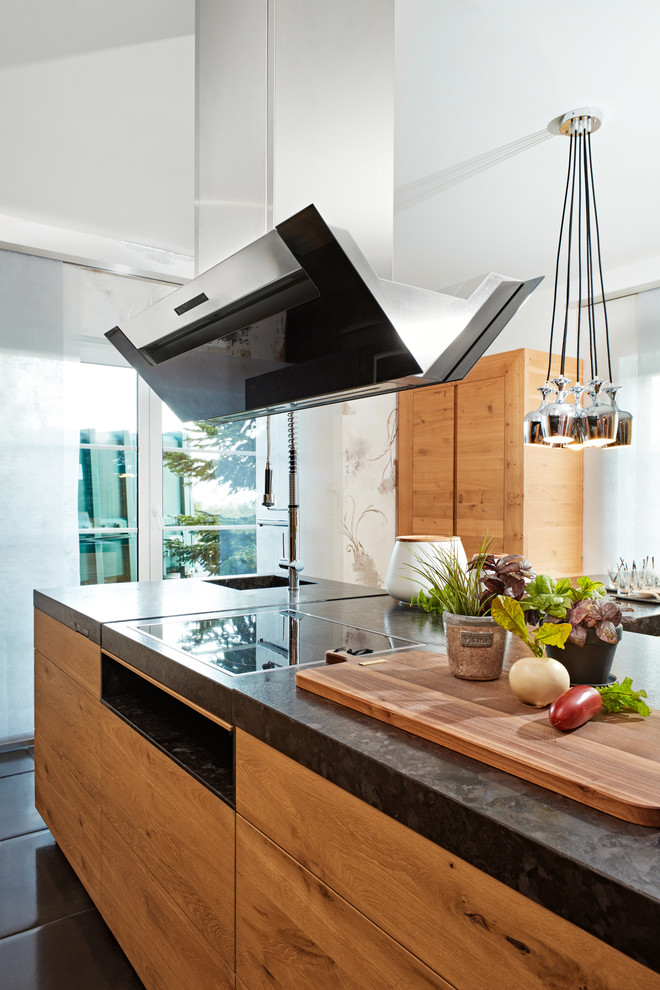 Idee per una cucina contemporanea di medie dimensioni con lavello da incasso, ante lisce, ante in legno chiaro, top in granito, elettrodomestici neri, pavimento in ardesia, pavimento nero e top nero