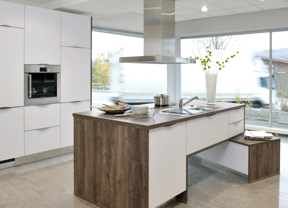 Immagine di una cucina minimal di medie dimensioni con lavello da incasso, ante lisce, ante bianche, top in legno, pavimento beige, top marrone e elettrodomestici in acciaio inossidabile
