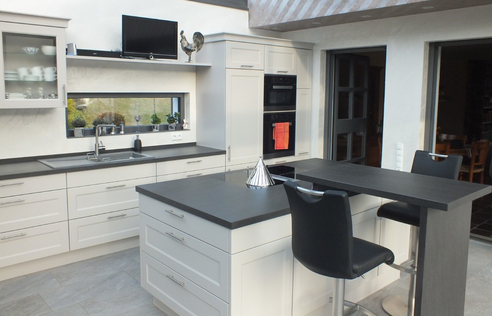 This is an example of a country open plan kitchen in Dortmund with grey cabinets and an island.
