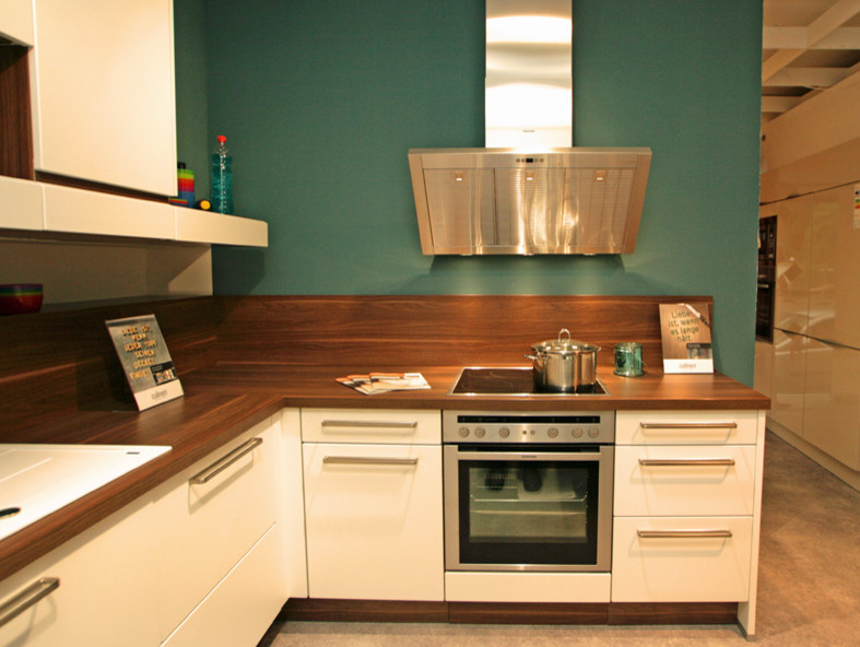 Foto på ett mellanstort funkis kök, med en enkel diskho, luckor med upphöjd panel, vita skåp, laminatbänkskiva, rostfria vitvaror och vinylgolv