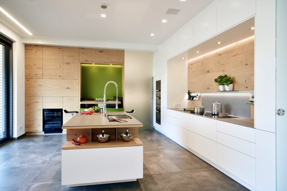 Inspiration for a medium sized contemporary galley kitchen/diner in Frankfurt with a double-bowl sink, flat-panel cabinets, light wood cabinets, black appliances, an island, grey floors, brown splashback, wood splashback and cement flooring.