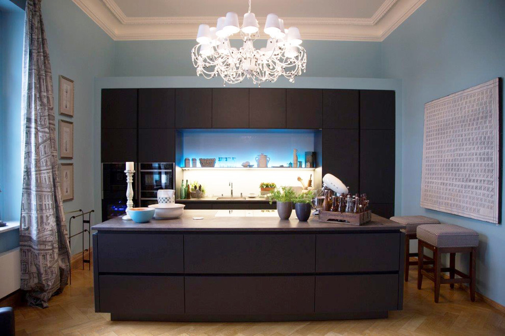 Immagine di una cucina design di medie dimensioni con ante lisce, ante nere, top in superficie solida, paraspruzzi multicolore, paraspruzzi con lastra di vetro, elettrodomestici neri e pavimento in legno massello medio