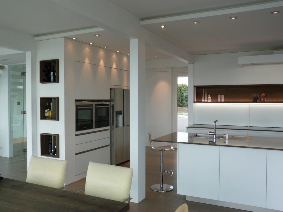 Offene Moderne Küche mit weißen Schränken und Küchengeräten aus Edelstahl in Berlin