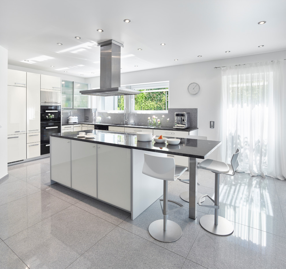 Design ideas for a medium sized contemporary l-shaped kitchen in Other with white cabinets, granite worktops, black appliances, an island, flat-panel cabinets and grey floors.