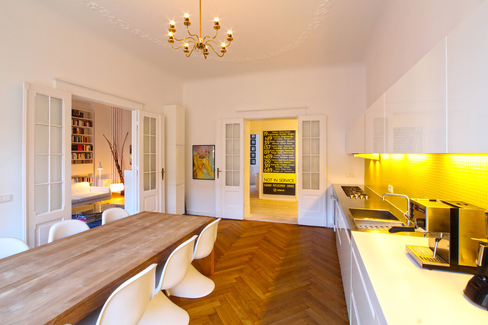 ベルリンにある広い北欧スタイルのおしゃれなキッチン (白いキャビネット、モザイクタイルのキッチンパネル、一体型シンク、フラットパネル扉のキャビネット、黄色いキッチンパネル、アイランドなし、無垢フローリング) の写真