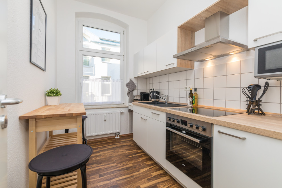 Bild på ett avskilt minimalistiskt linjärt kök, med laminatgolv och brunt golv