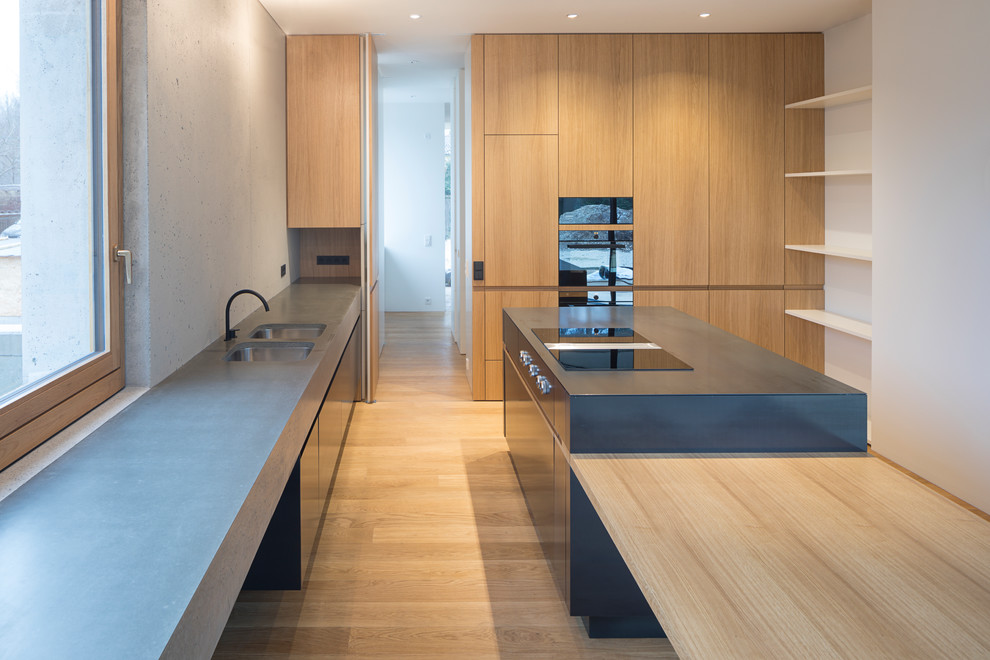 Inspiration for a modern kitchen in Munich with a submerged sink, flat-panel cabinets, concrete worktops, black appliances and grey worktops.