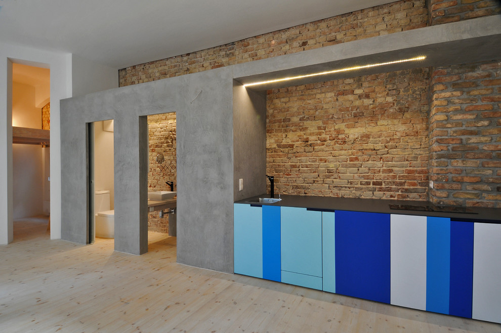 Single-wall open plan kitchen in Berlin with flat-panel cabinets, blue cabinets, light hardwood flooring and no island.