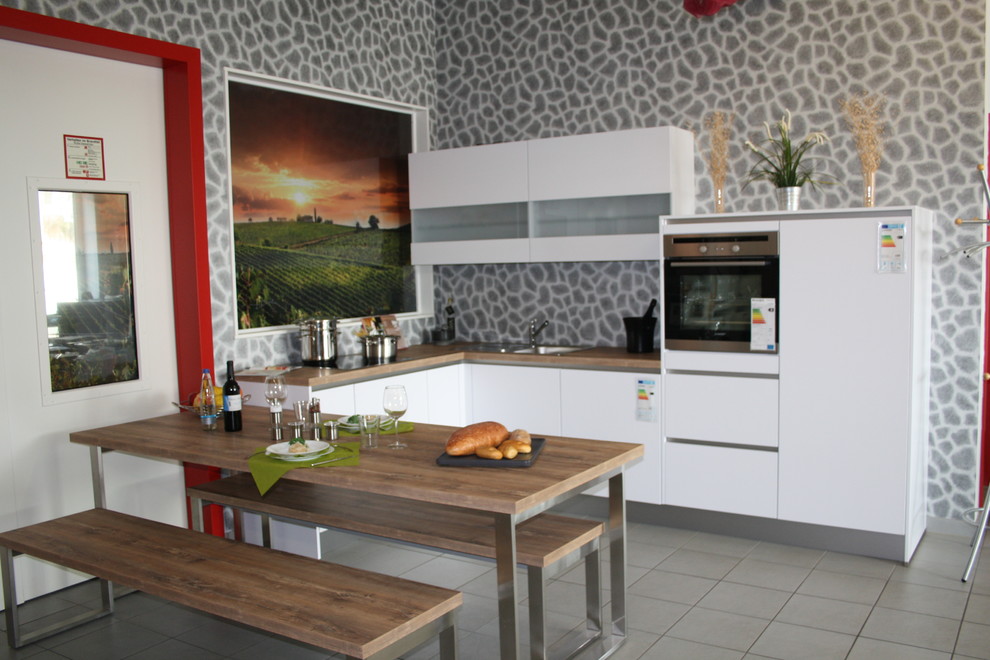 Свежая идея для дизайна: кухня-гостиная в современном стиле с белым фартуком и техникой из нержавеющей стали - отличное фото интерьера
