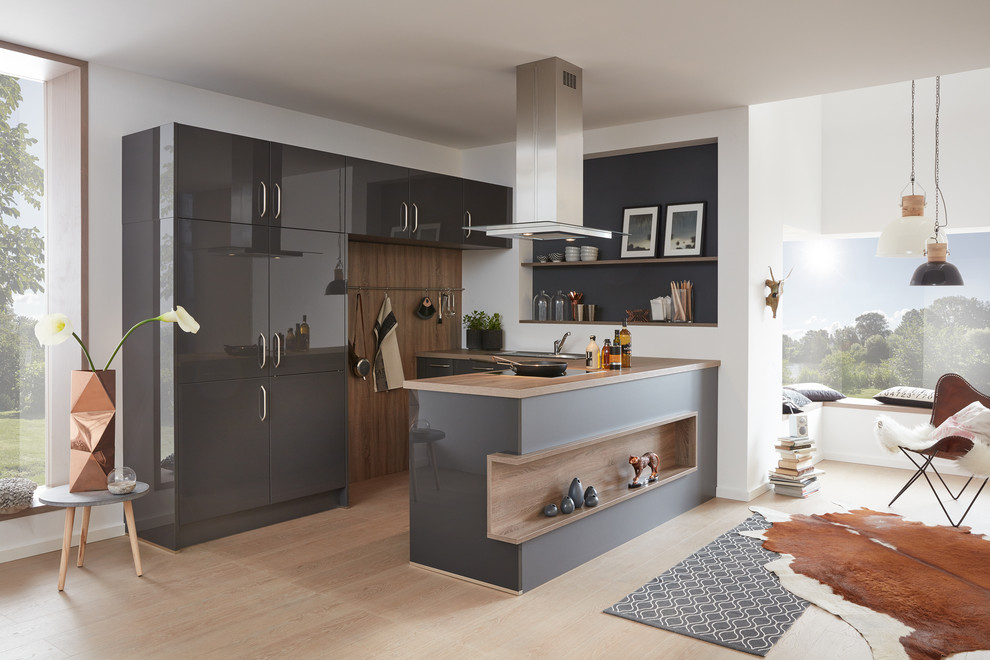 Foto de cocina actual de tamaño medio con puertas de armario grises, salpicadero blanco, electrodomésticos de acero inoxidable y península