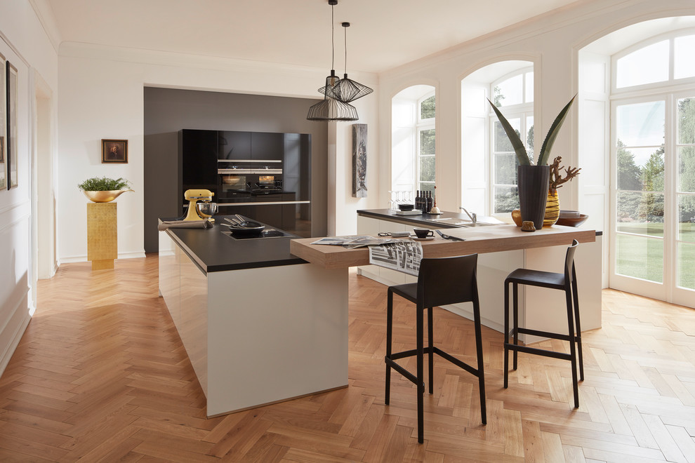 Idee per una grande cucina ad U minimal con elettrodomestici neri e pavimento in legno massello medio