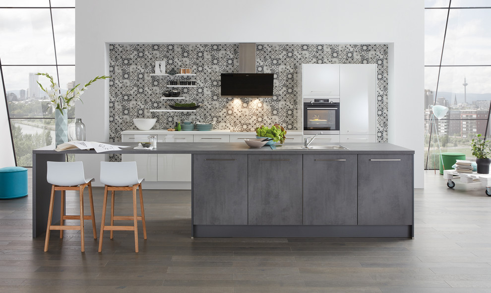 Einzeilige, Mittelgroße Moderne Küche mit grauen Schränken, bunter Rückwand, Rückwand aus Keramikfliesen, Küchengeräten aus Edelstahl, dunklem Holzboden und Kücheninsel in Hannover