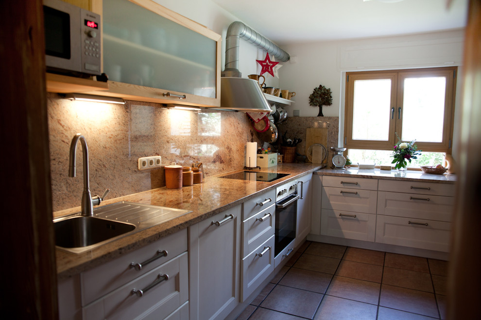 Cette image montre une cuisine design en L et bois brun avec un plan de travail en granite.