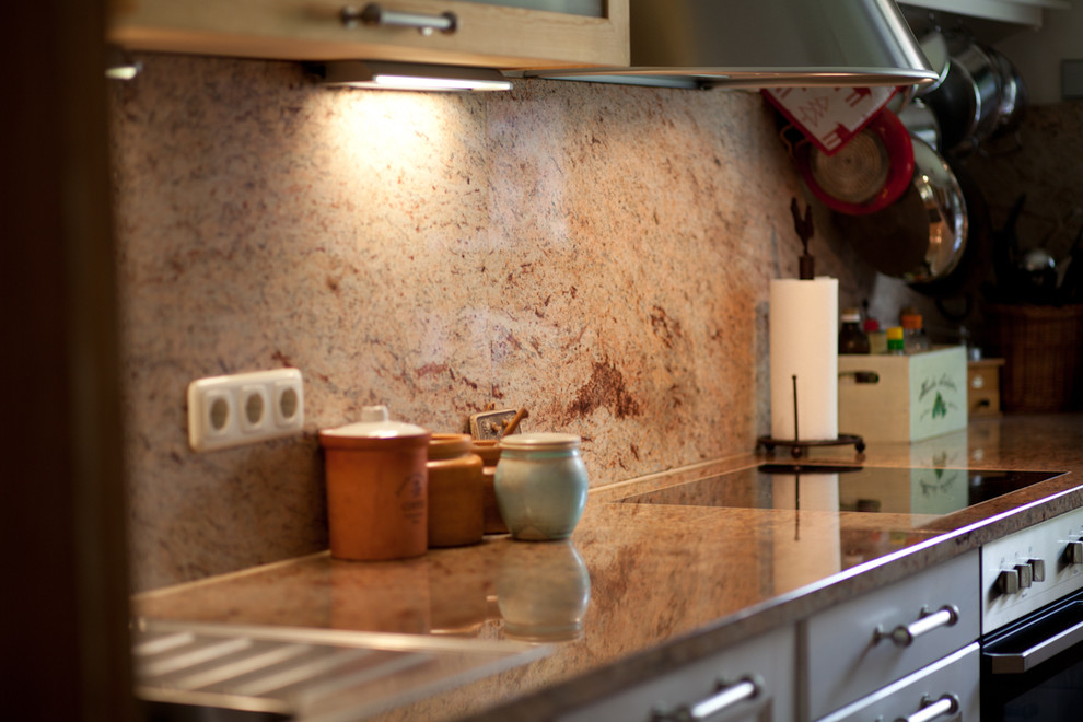 Exemple d'une cuisine tendance en L et bois brun avec un plan de travail en granite.