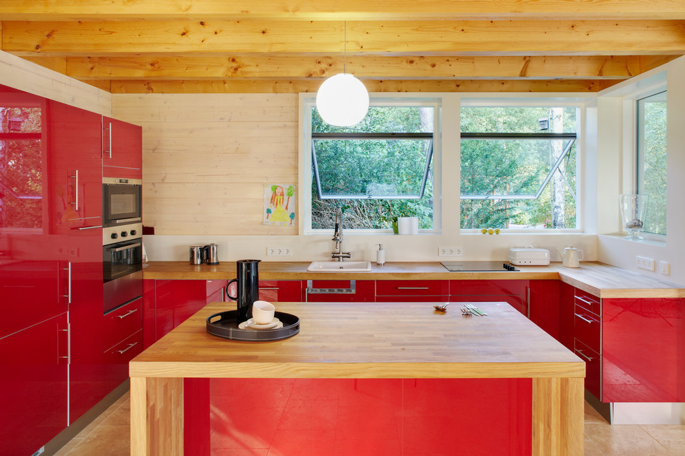 Идея дизайна: большая п-образная, отдельная кухня в современном стиле с плоскими фасадами, красными фасадами, деревянной столешницей, накладной мойкой, островом, белым фартуком и техникой из нержавеющей стали