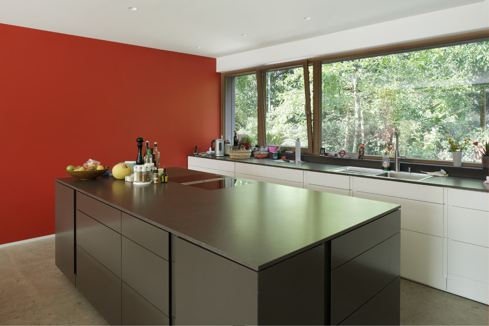 Example of a large trendy single-wall enclosed kitchen design in Frankfurt with a drop-in sink, flat-panel cabinets, black cabinets and an island