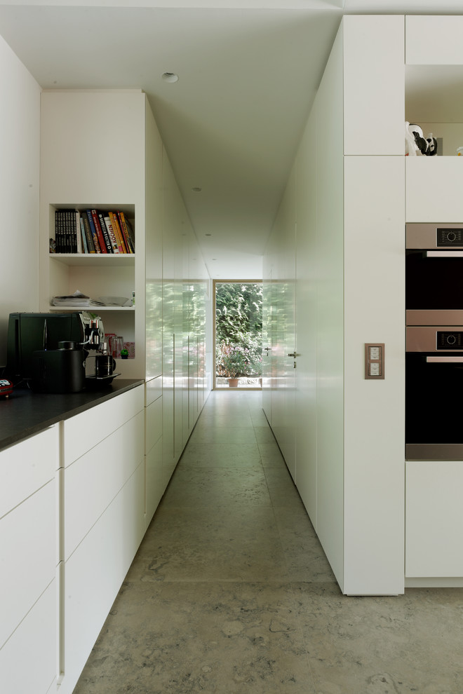 Moderne grifflose Küche mit flächenbündigen Schrankfronten, weißen Schränken und Küchengeräten aus Edelstahl in Frankfurt am Main