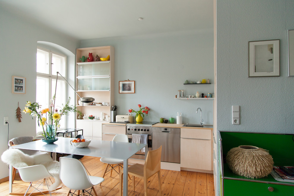 Inspiration for a medium sized scandinavian l-shaped kitchen/diner in Berlin with flat-panel cabinets, beige cabinets, wood worktops, blue splashback, no island, a built-in sink, stainless steel appliances, light hardwood flooring and brown floors.