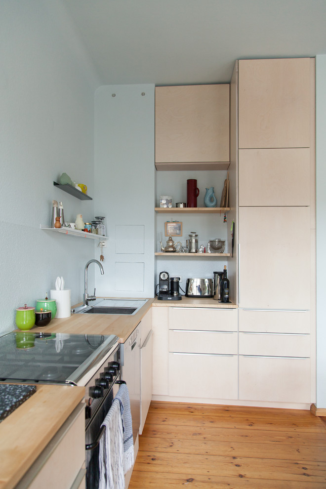Photo of a medium sized scandinavian l-shaped kitchen/diner in Berlin with flat-panel cabinets, beige cabinets, wood worktops, blue splashback, no island, a built-in sink, stainless steel appliances, light hardwood flooring and brown floors.