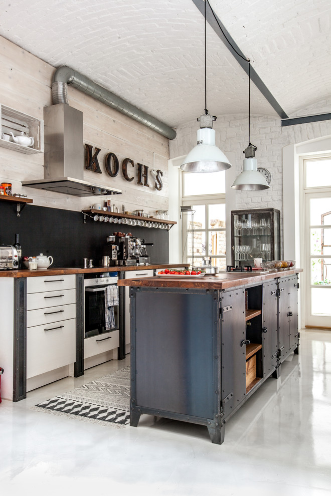 Zweizeilige Industrial Küche mit flächenbündigen Schrankfronten, weißen Schränken, Küchenrückwand in Schwarz und Kücheninsel in Sonstige