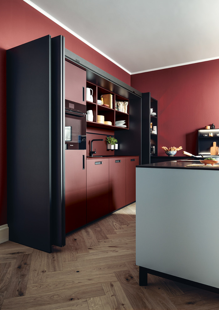 Large zen l-shaped open concept kitchen photo in Nuremberg with flat-panel cabinets, black cabinets, red backsplash, black appliances, an island and white countertops