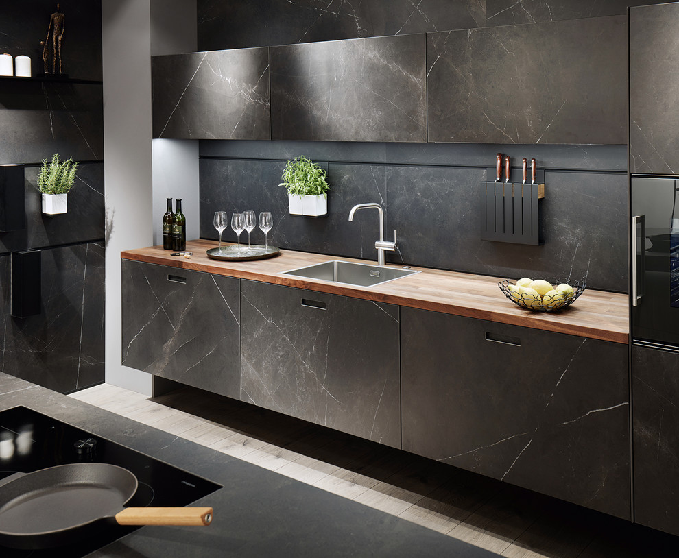 Offene Moderne Küche in L-Form mit schwarzen Schränken, Arbeitsplatte aus Holz, Küchenrückwand in Schwarz, schwarzen Elektrogeräten, Kücheninsel und brauner Arbeitsplatte in Nürnberg