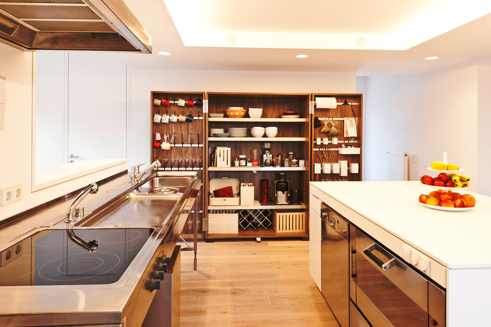 Inspiration pour une cuisine nordique de taille moyenne avec un évier intégré, un placard à porte plane, des portes de placard blanches, un sol en bois brun, îlot et un électroménager en acier inoxydable.