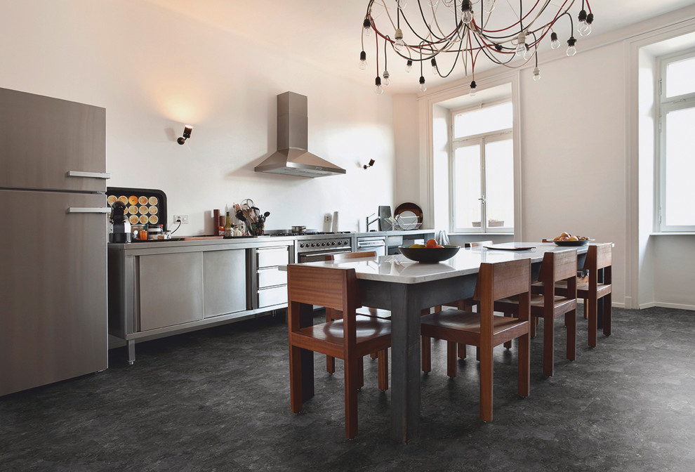 Imagen de cocina comedor lineal, urbana, de tamaño medio, sin isla, con fregadero integrado, electrodomésticos de acero inoxidable, suelo vinílico, puertas de armario en acero inoxidable, encimera de acero inoxidable y salpicadero blanco