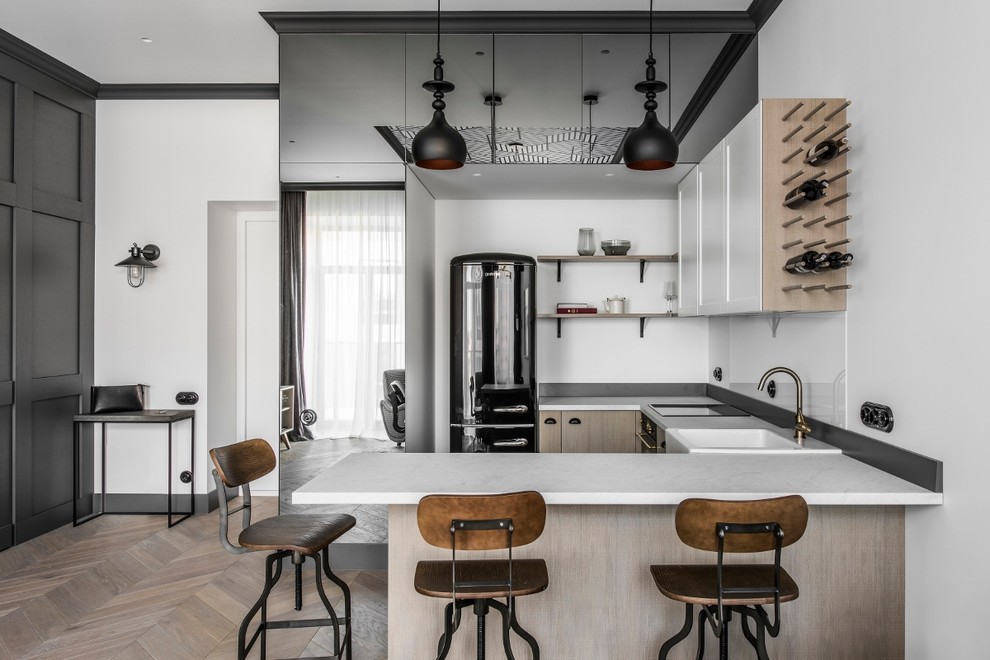 Inspiration for a scandinavian u-shaped medium tone wood floor and brown floor kitchen remodel in Stuttgart with white cabinets, white backsplash, white countertops, a farmhouse sink, recessed-panel cabinets, glass sheet backsplash, black appliances and a peninsula