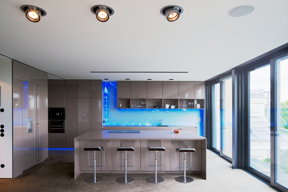 Bild på ett stort funkis linjärt kök och matrum, med släta luckor, beige skåp, blått stänkskydd, glaspanel som stänkskydd, svarta vitvaror och en köksö