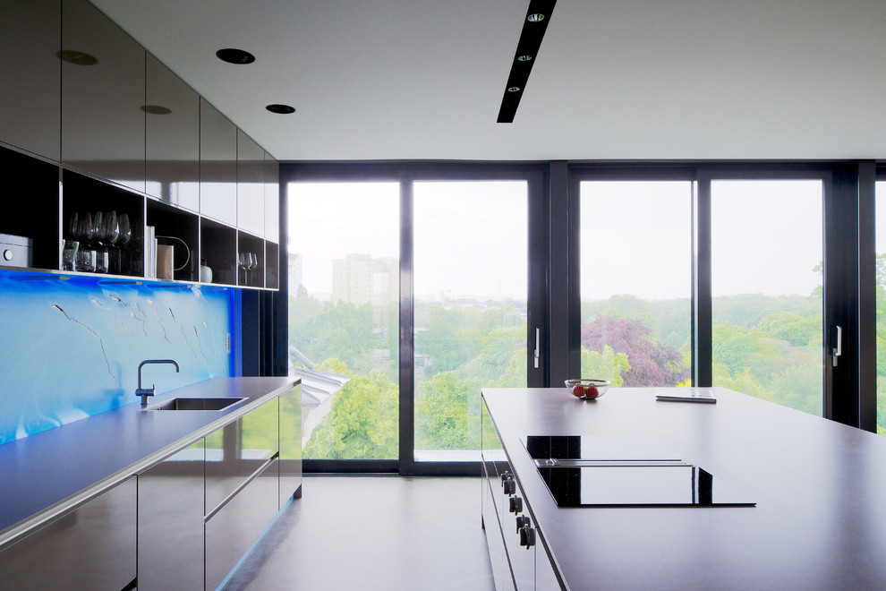 Стильный дизайн: большая прямая кухня в современном стиле с обеденным столом, плоскими фасадами, бежевыми фасадами, синим фартуком, фартуком из стекла, черной техникой и островом - последний тренд