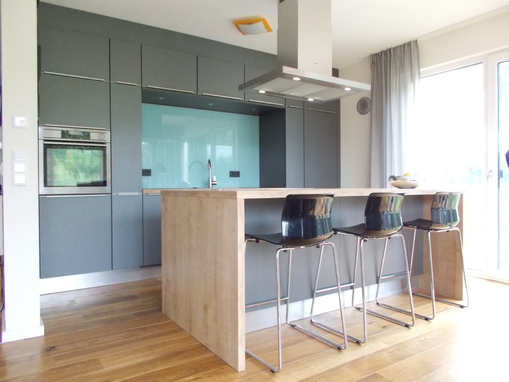 Offene, Zweizeilige Moderne Küche mit grauen Schränken und Kücheninsel in Hamburg
