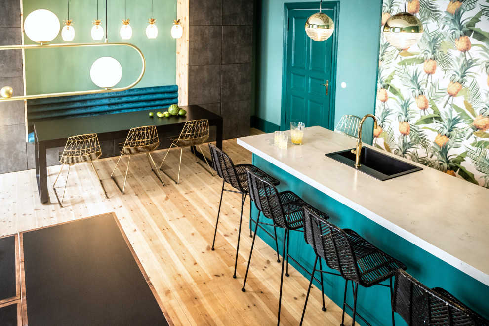 Moderne Wohnküche mit türkisfarbenen Schränken, Betonarbeitsplatte, schwarzen Elektrogeräten, hellem Holzboden, Kücheninsel, braunem Boden, grauer Arbeitsplatte und Tapetendecke in Berlin