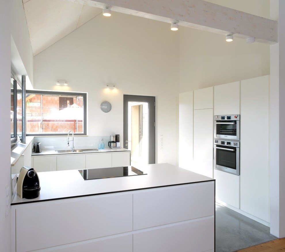Bild på ett avskilt, mellanstort funkis kök, med släta luckor, vita skåp, vitt stänkskydd, glaspanel som stänkskydd, rostfria vitvaror, en halv köksö och en nedsänkt diskho