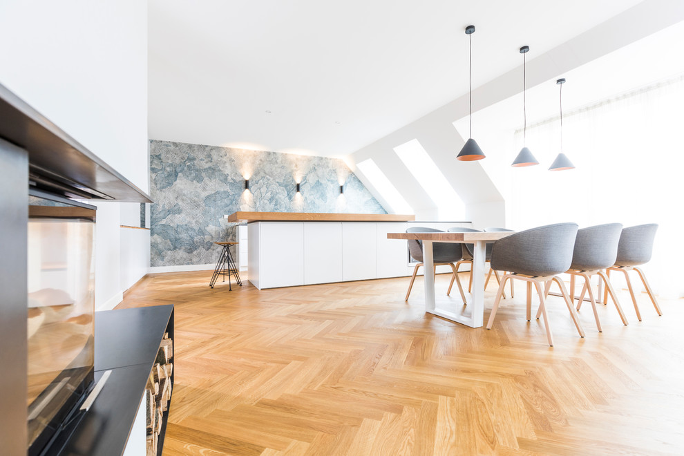 На фото: большая угловая кухня в скандинавском стиле с обеденным столом, плоскими фасадами, белыми фасадами, разноцветным фартуком, паркетным полом среднего тона, полуостровом, коричневым полом и обоями на стенах