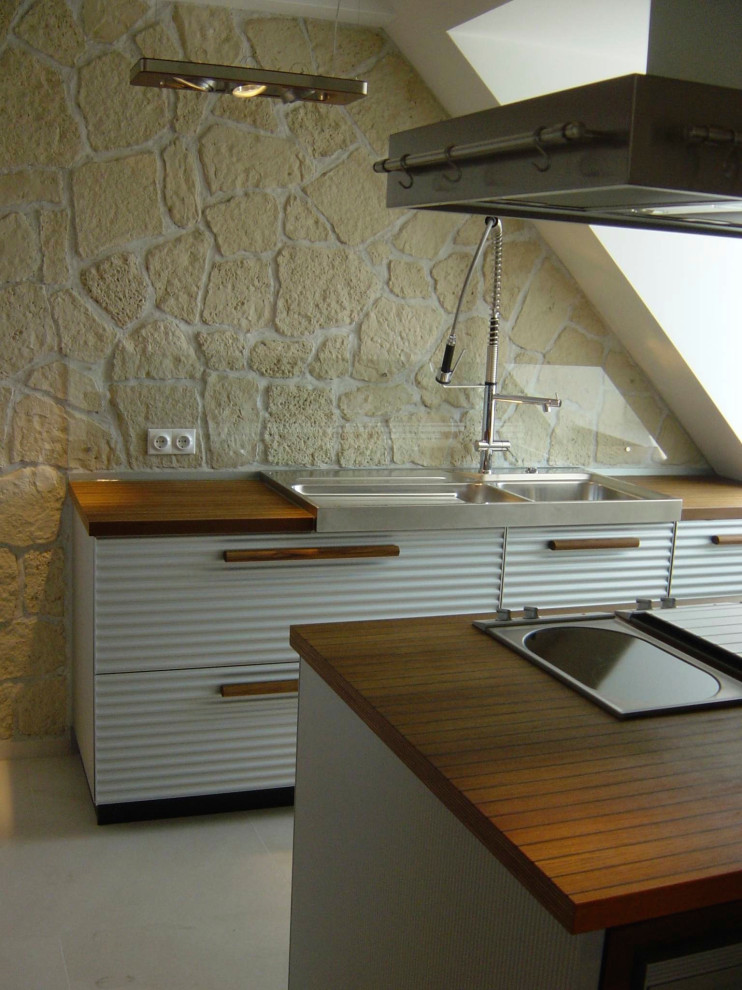 Idéer för ett mellanstort modernt linjärt kök, med en dubbel diskho, luckor med upphöjd panel, träbänkskiva, stänkskydd i kalk, rostfria vitvaror, kalkstensgolv, en köksö och beiget golv