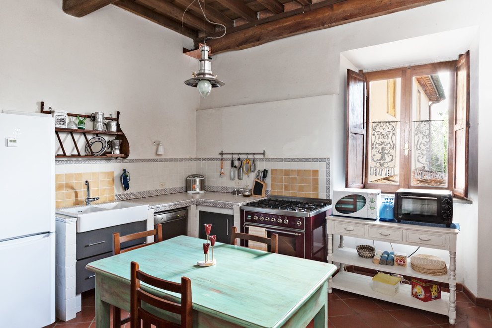 Landhaus Küche mit integriertem Waschbecken, Rückwand aus Keramikfliesen, Terrakottaboden und Mauersteinen in Florenz