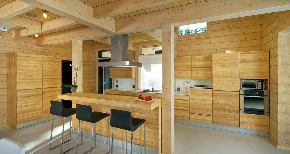 На фото: угловая кухня в скандинавском стиле с плоскими фасадами, светлыми деревянными фасадами и островом