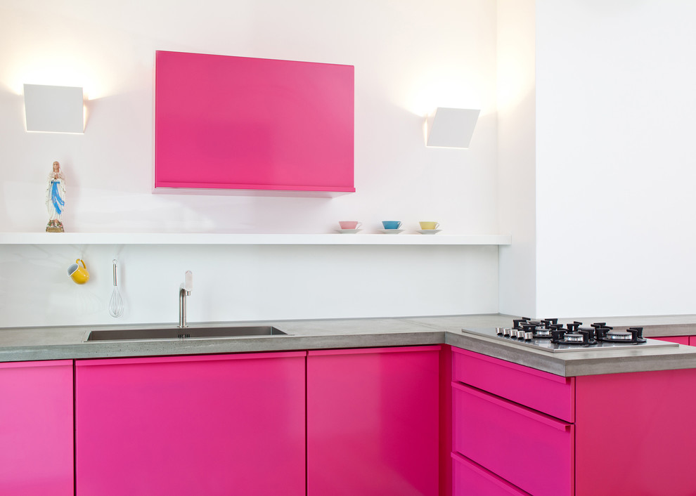 Immagine di una cucina design di medie dimensioni con lavello da incasso, ante lisce, top in cemento, elettrodomestici da incasso e penisola