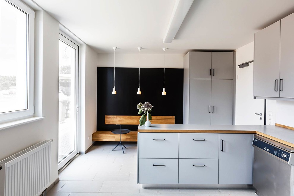 Immagine di una cucina scandinava chiusa e di medie dimensioni con ante lisce, ante grigie, top in legno, pavimento in gres porcellanato, penisola e elettrodomestici in acciaio inossidabile