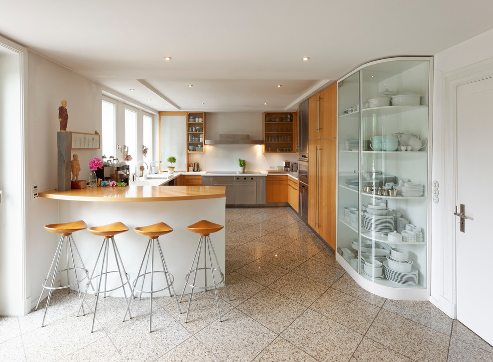 Enclosed kitchen - large contemporary u-shaped enclosed kitchen idea in Hamburg with flat-panel cabinets, medium tone wood cabinets, white backsplash, stainless steel appliances and a peninsula