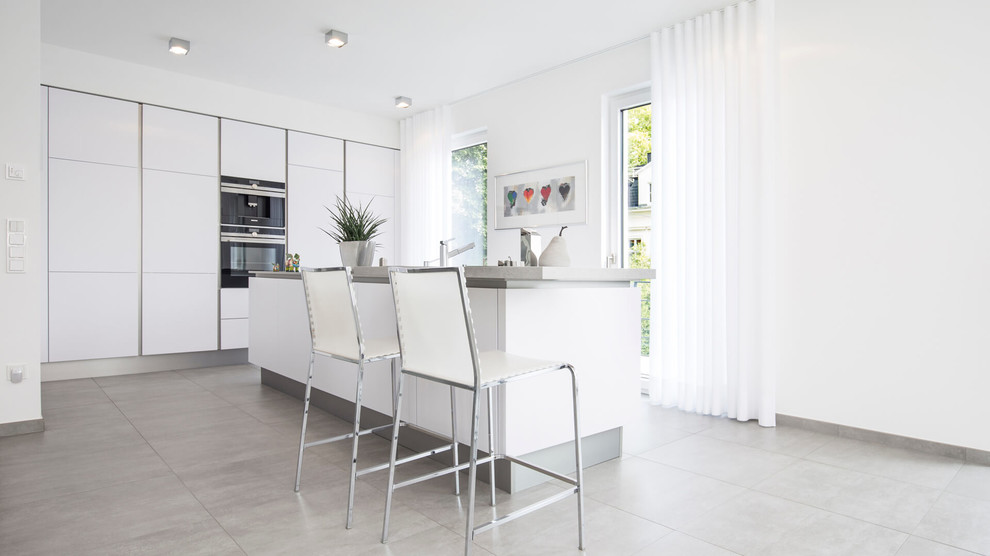Inspiration for a large contemporary single-wall open plan kitchen in Dortmund with flat-panel cabinets, white cabinets, concrete worktops, black appliances, cement flooring, a breakfast bar and grey floors.