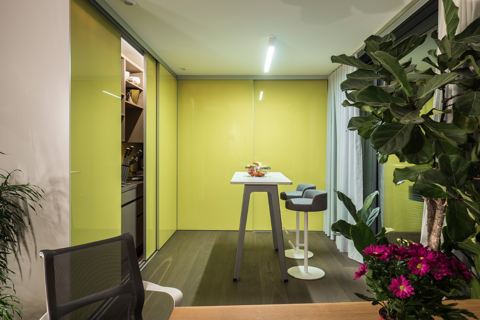 Kleine Moderne Küche in L-Form mit Vorratsschrank, flächenbündigen Schrankfronten, grünen Schränken, Elektrogeräten mit Frontblende, dunklem Holzboden, Kücheninsel und braunem Boden in Stuttgart