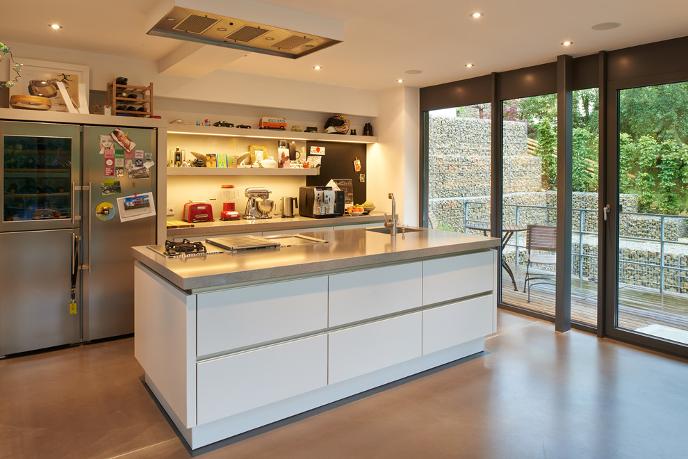 Inspiration for a medium sized contemporary single-wall open plan kitchen in Other with an integrated sink, white splashback, stainless steel appliances, flat-panel cabinets, white cabinets and an island.